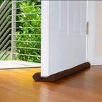 Brown draft stopper at bottom of white door on hardwood floor, blocks drafts and noise